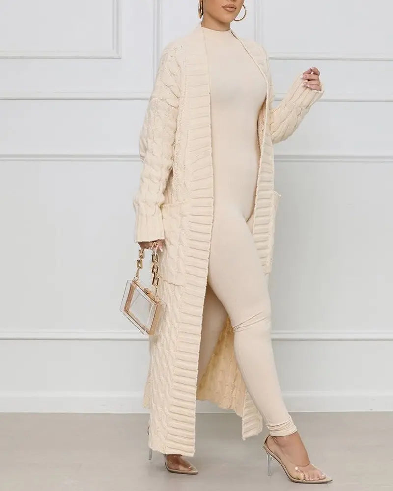Person wearing a long beige cardigan over a matching outfit against a white background